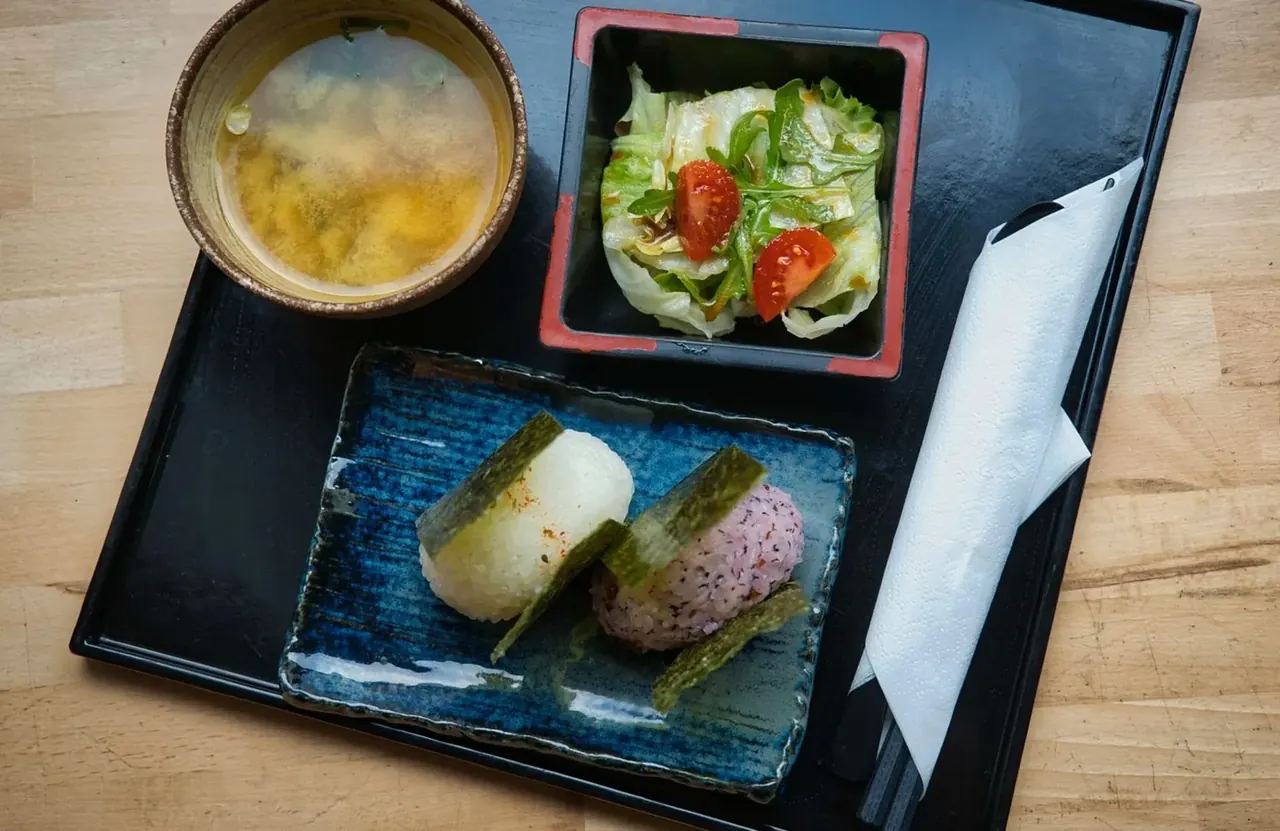 朝食のイメージ写真(味噌汁、サラダ、おにぎりを載せたお盆)